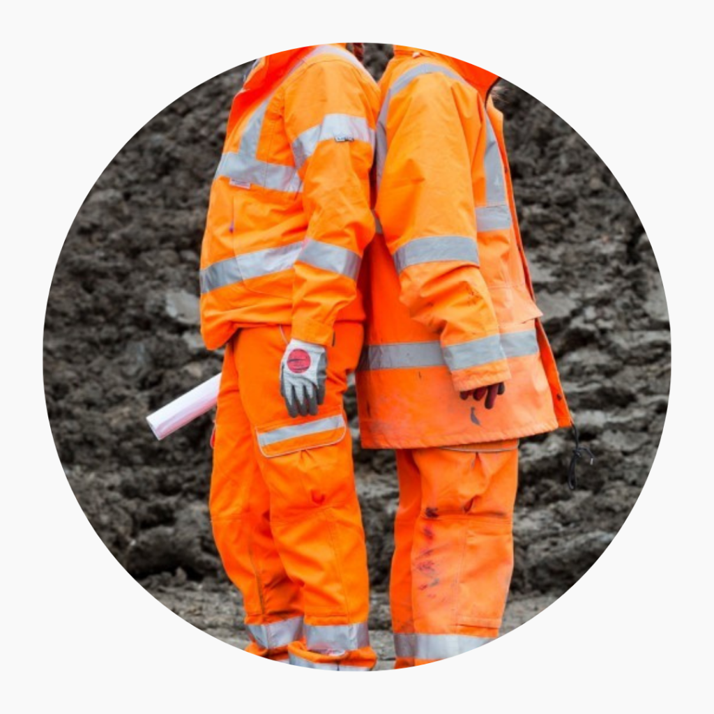 Old style and new syle safety clothing commissioned by Transport for London. two figures standing back to back. the llef tin modern fitting bright orange PPE. The right in oversized kit.