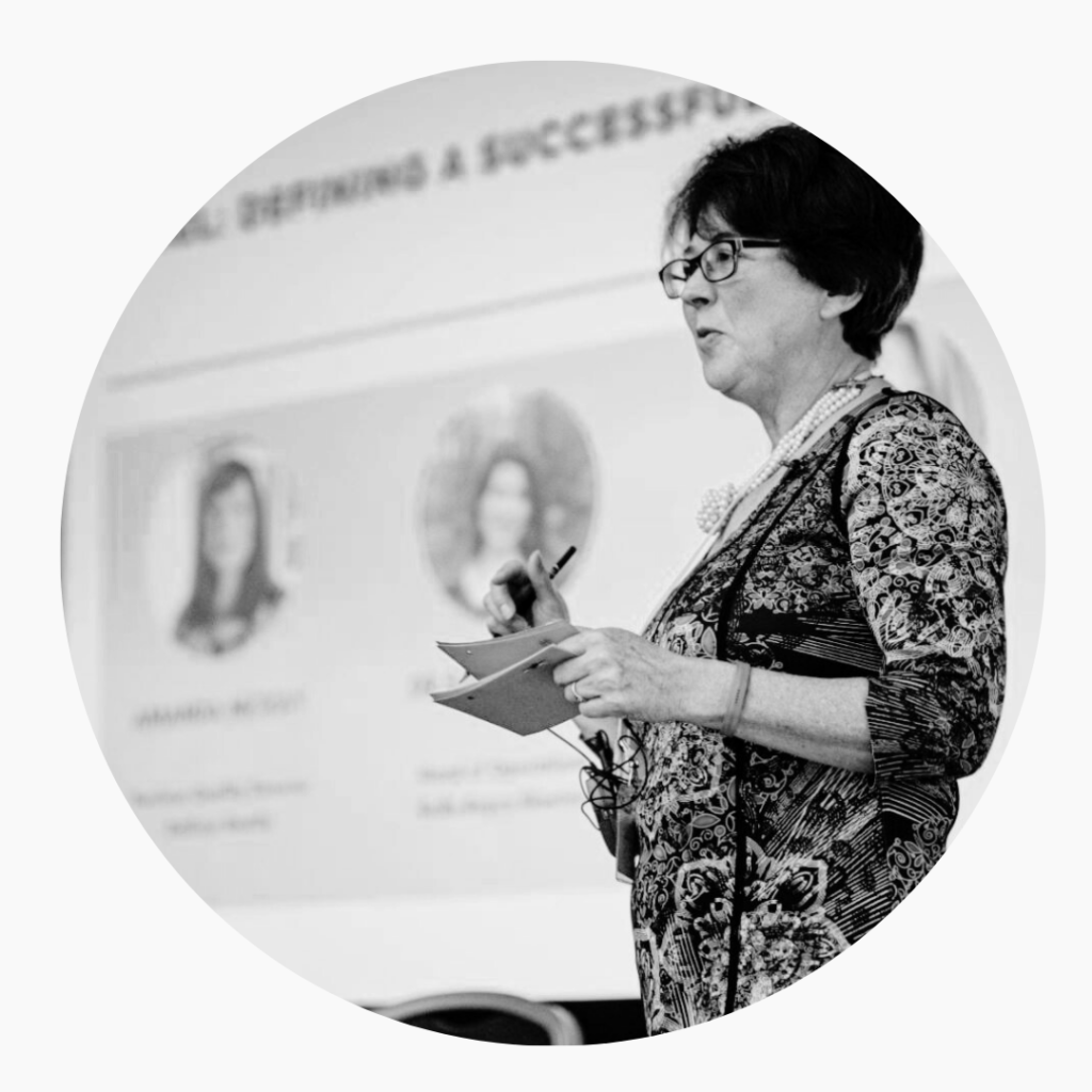 Black and white photo of Dr Jan using her hands expressively and facilitating discussion at an event